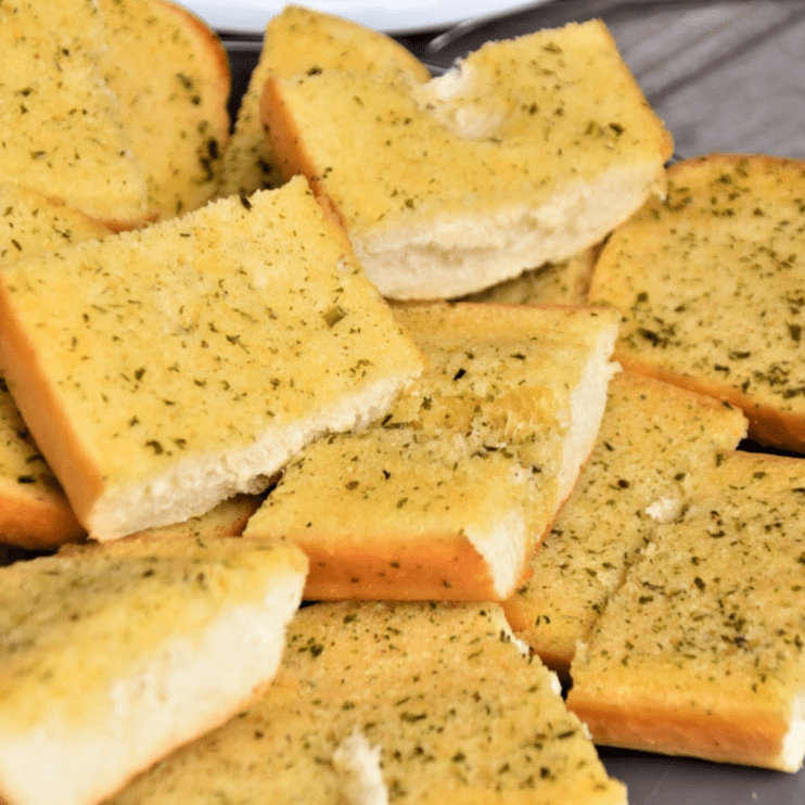 Herb seasoned garlic bread slices arranged on a plate.