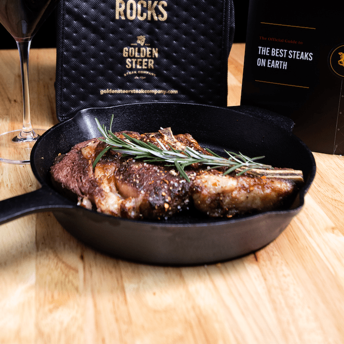 Skillet-seared ribeye with rosemary in cast iron pan, Golden Steer bag and steak guide behind