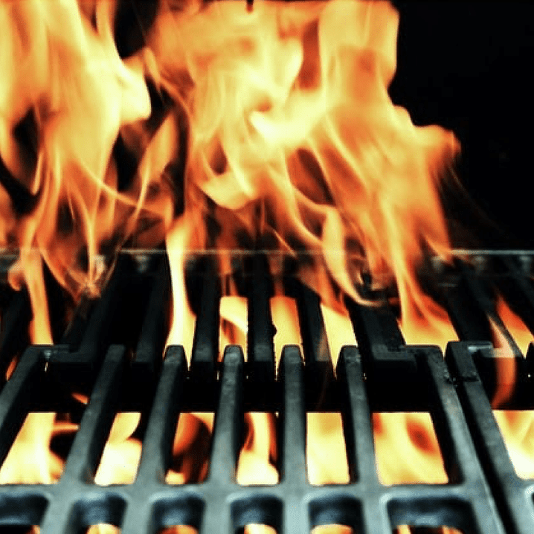 Grill grates with large orange flames rising between the metal bars