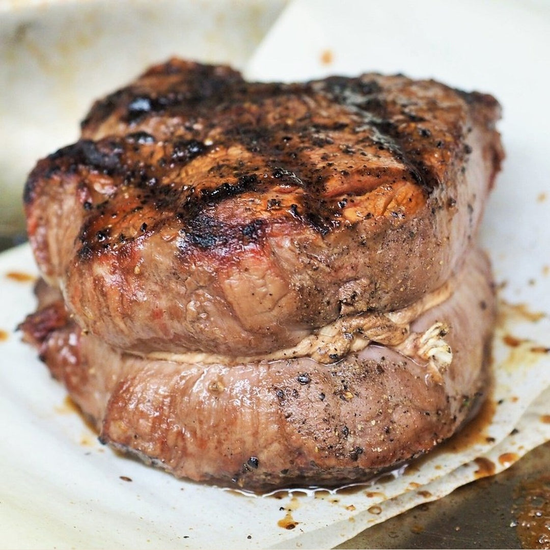Thick grilled filet mignon steak with seared crust and juices on parchment paper