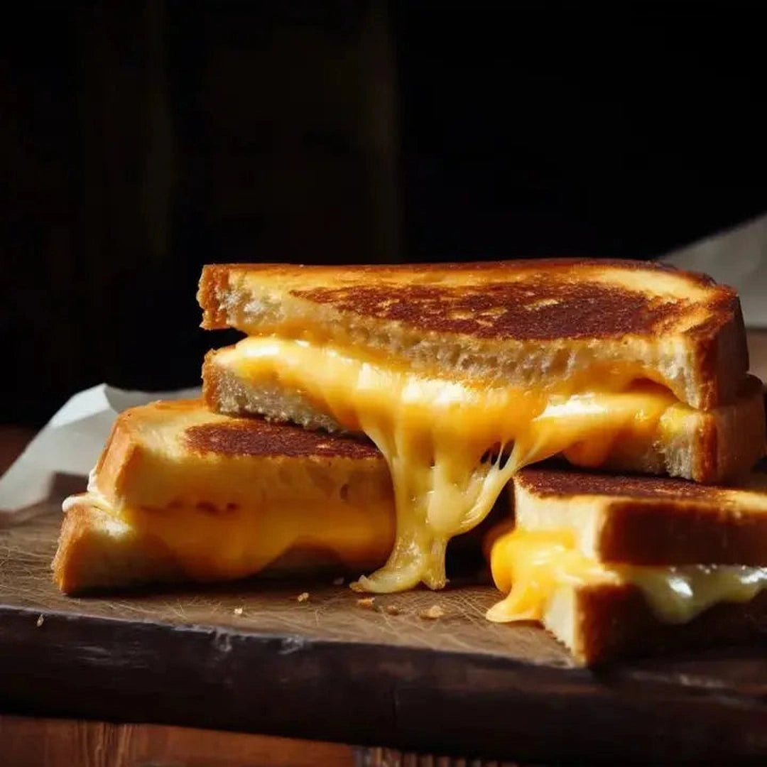 Toasty grilled cheese sandwich with gooey melted cheese stretching between stacked halves on a wooden board.