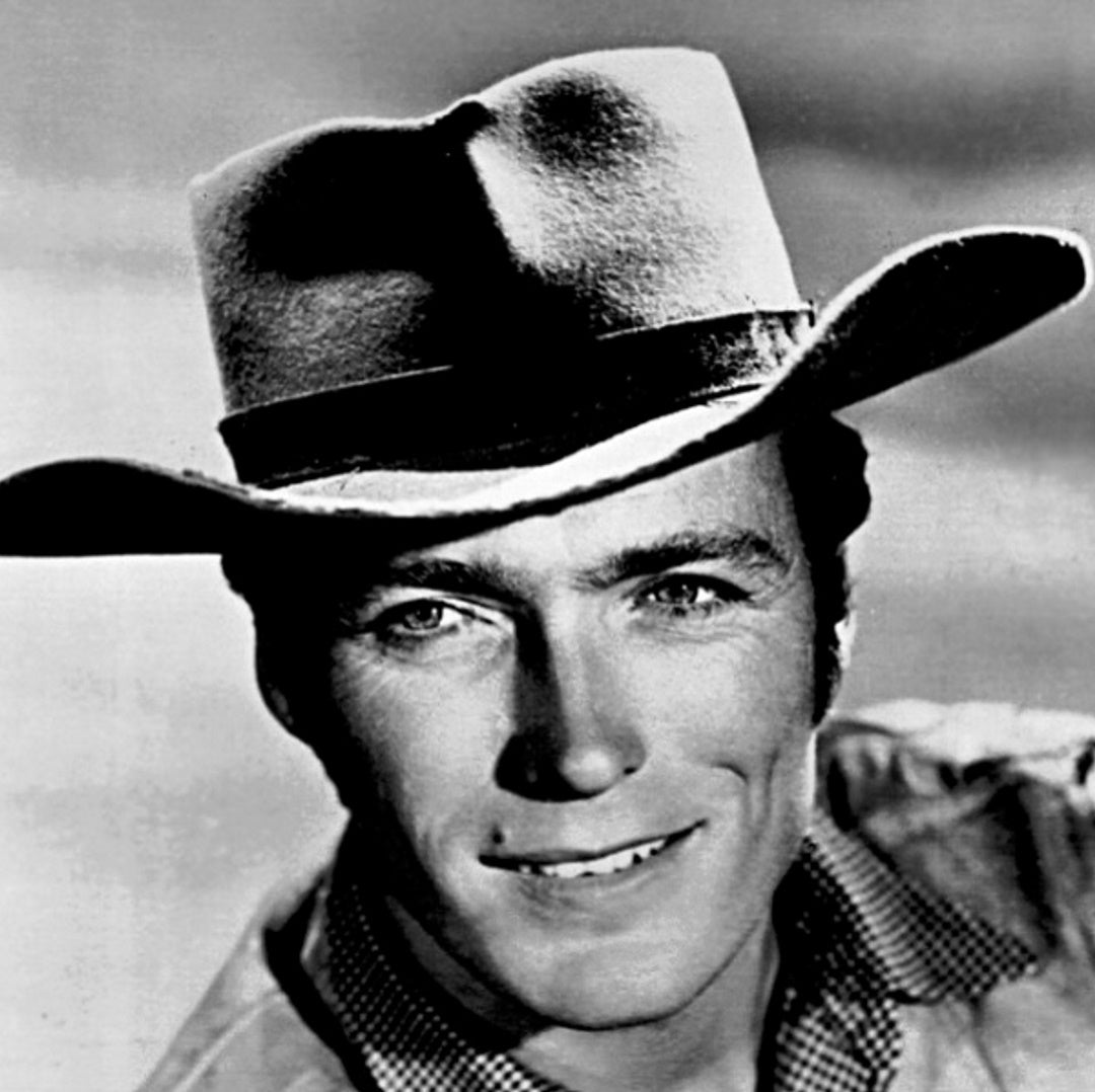 Black-and-white close-up headshot of Clint Eastwood wearing a wide-brim cowboy hat and checkered shirt collar