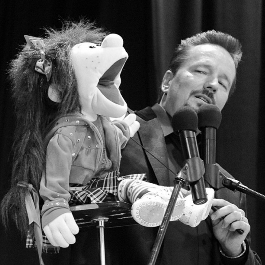 Ventriloquist Terry Fator performing onstage with a seated puppet and two microphones