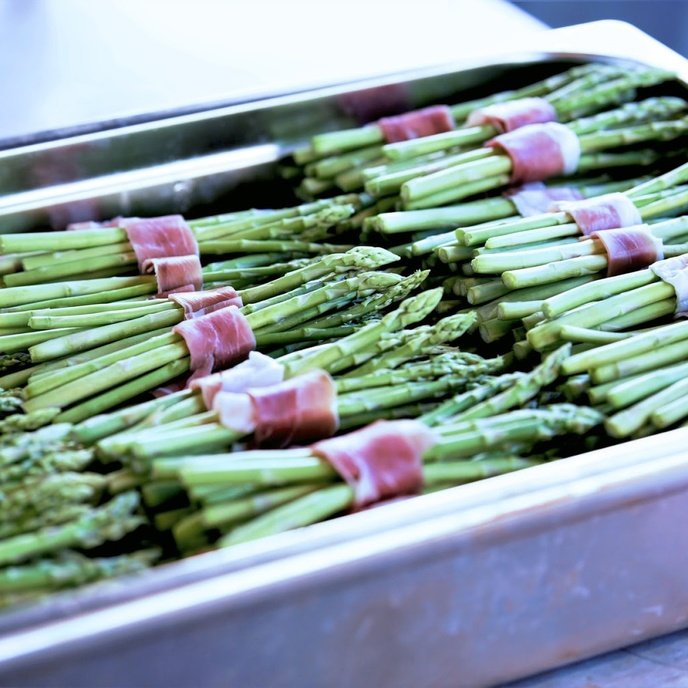 Asparagus bundles wrapped in bacon on a baking tray