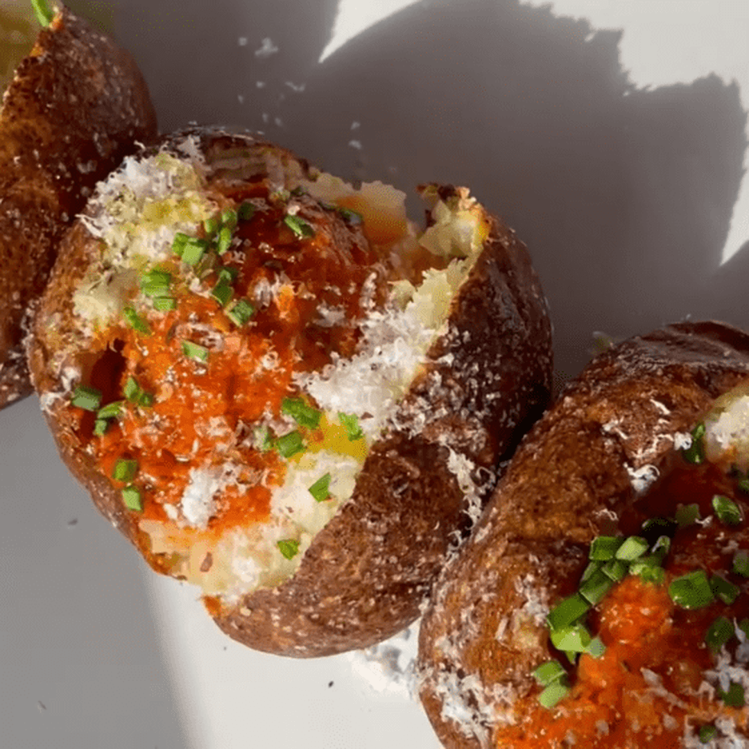 Baked potato halves topped with tangy tomato garlic butter and chopped chives