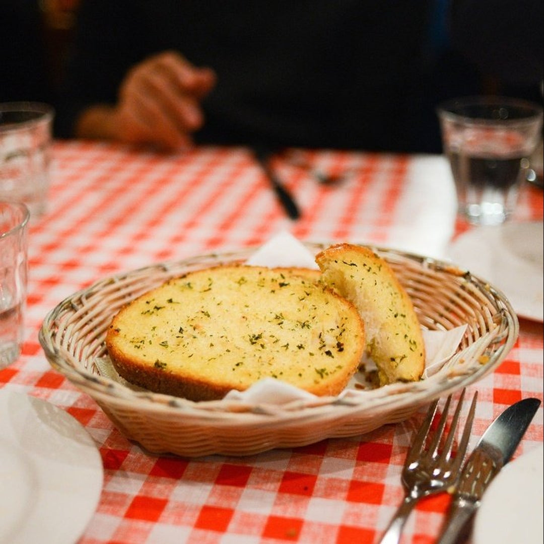 Garlic bread slices in a wicker basket on a red checkered tablecloth