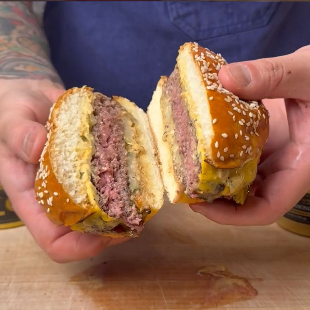 Cross section of a sesame seed bun cheeseburger with a beef patty and melted cheese