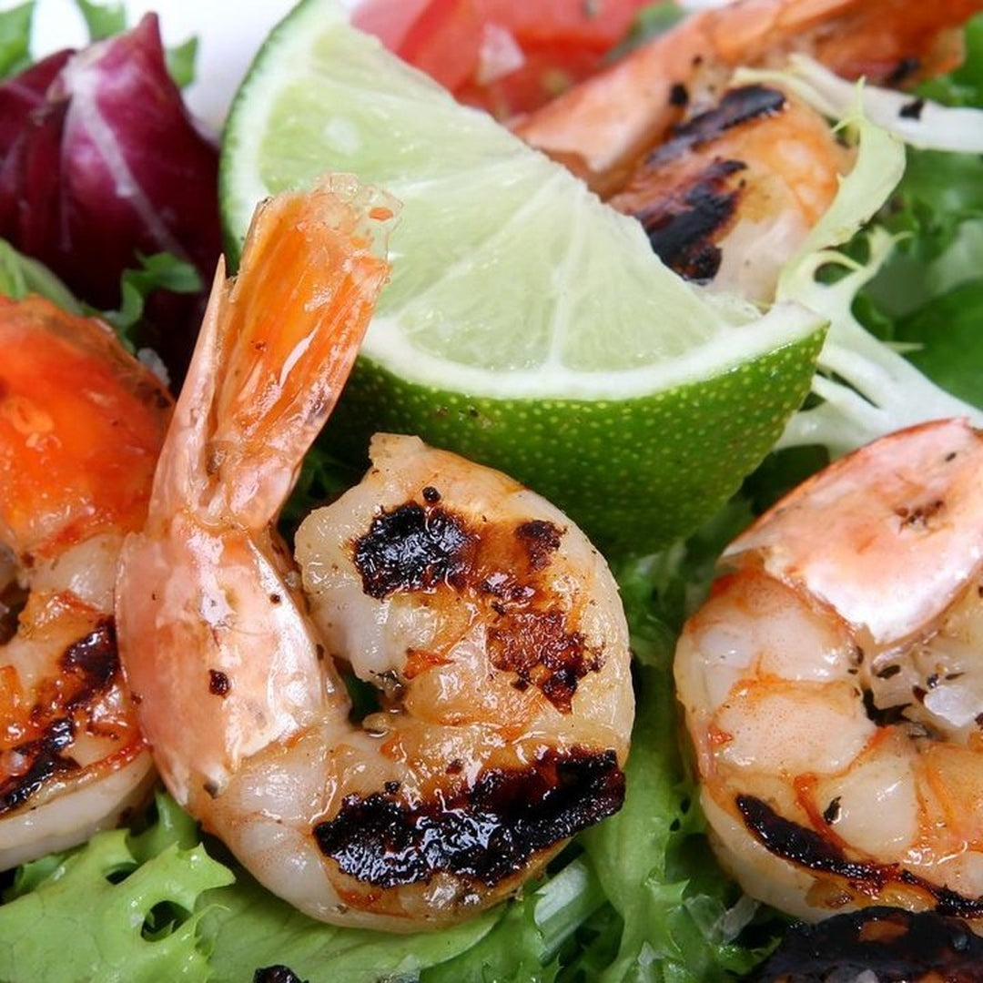 Grilled shrimp with lime wedge and fresh greens on a plate