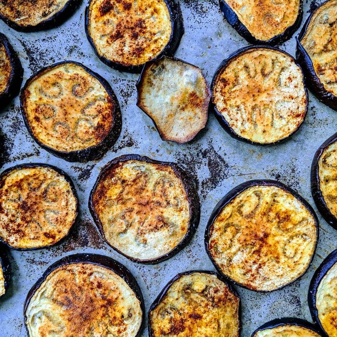 Roasted eggplant slices on a sheet pan with golden browning