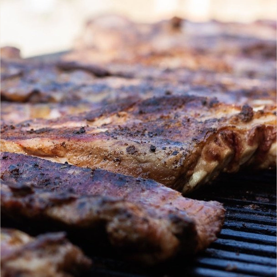 Juicy baby back ribs cooking on a grill with a smoky crust