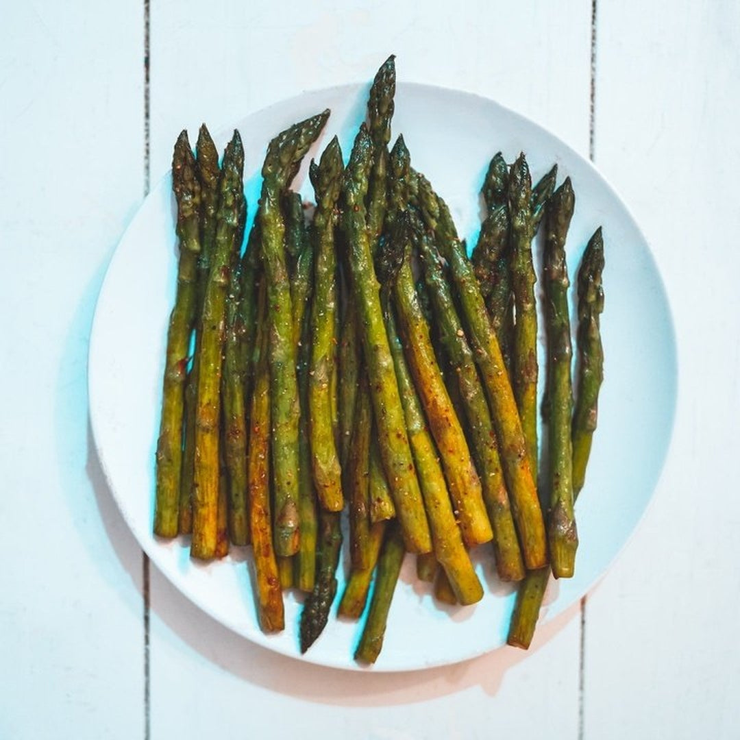 Roasted asparagus spears arranged on a white plate