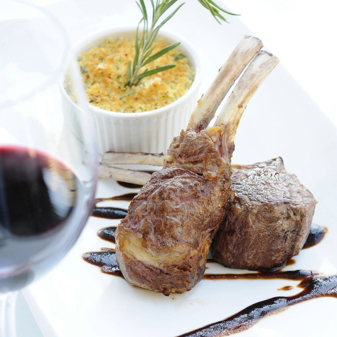 Rack of lamb with rosemary garnish and balsamic glaze on a white plate