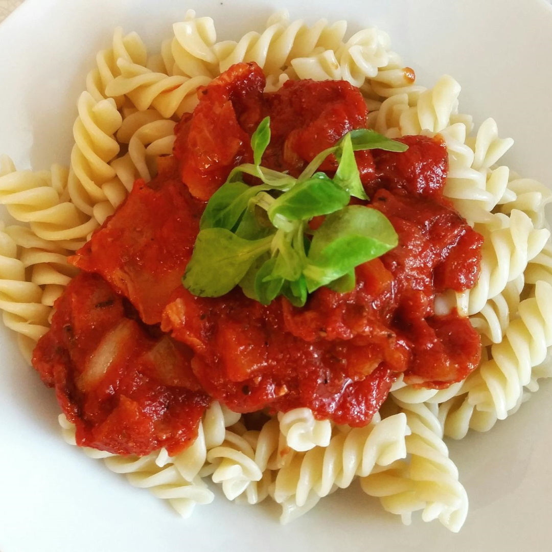 Fusilli pasta topped with chunky tomato sauce and a fresh basil leaf