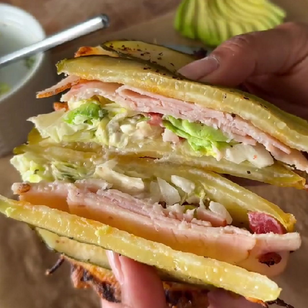 Cross section of a stacked pickle bread sandwich filled with ham turkey and lettuce