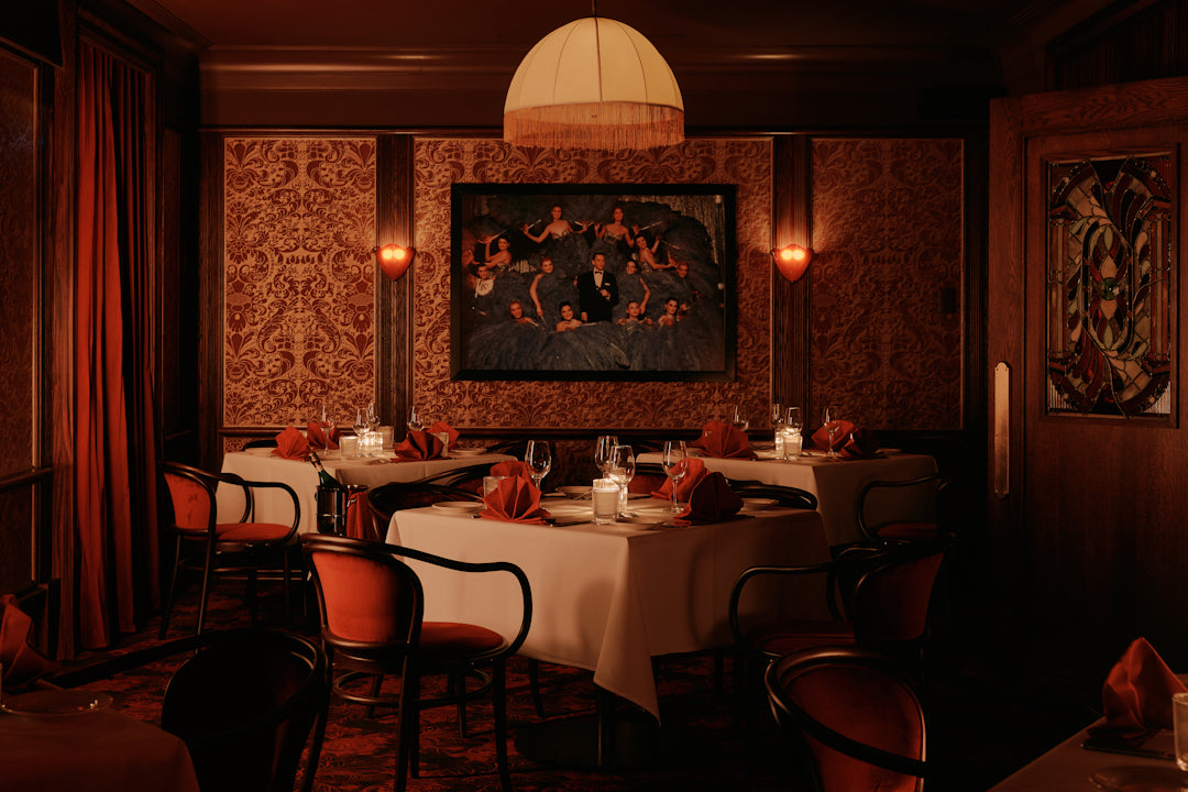 Dining room with tables, chairs, and a framed image of Frank SInatra surrounded by showgirls on the wall.