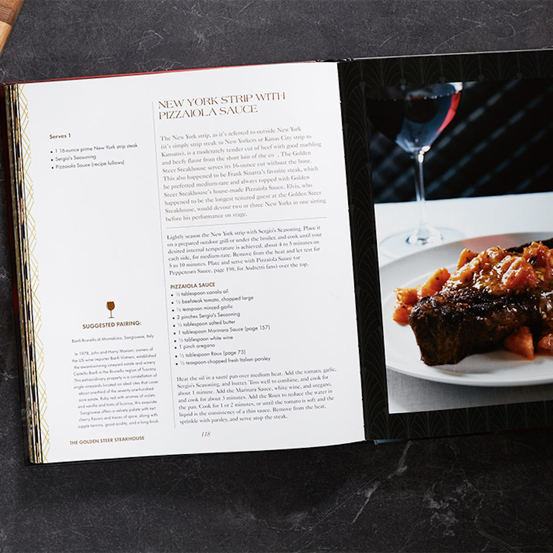 Open cookbook showing New York Strip with Pizzaiola Sauce recipe beside a plated steak and a wine glass