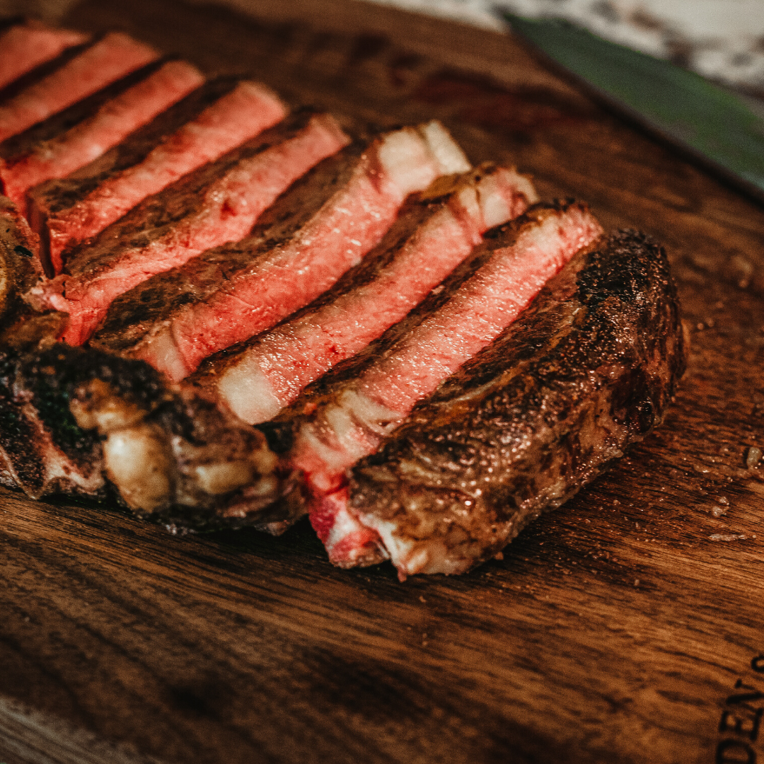 Close-up of sliced steak showcasing medium-rare pink center and seared crust on a wooden cutting board