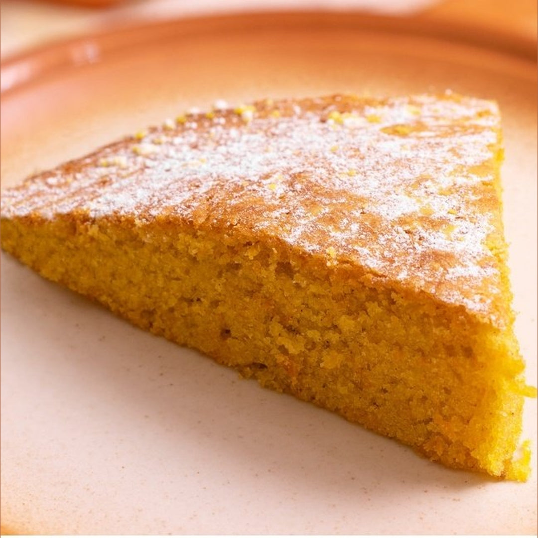Triangular slice of golden-brown cornbread dusted with powdered sugar on a plate