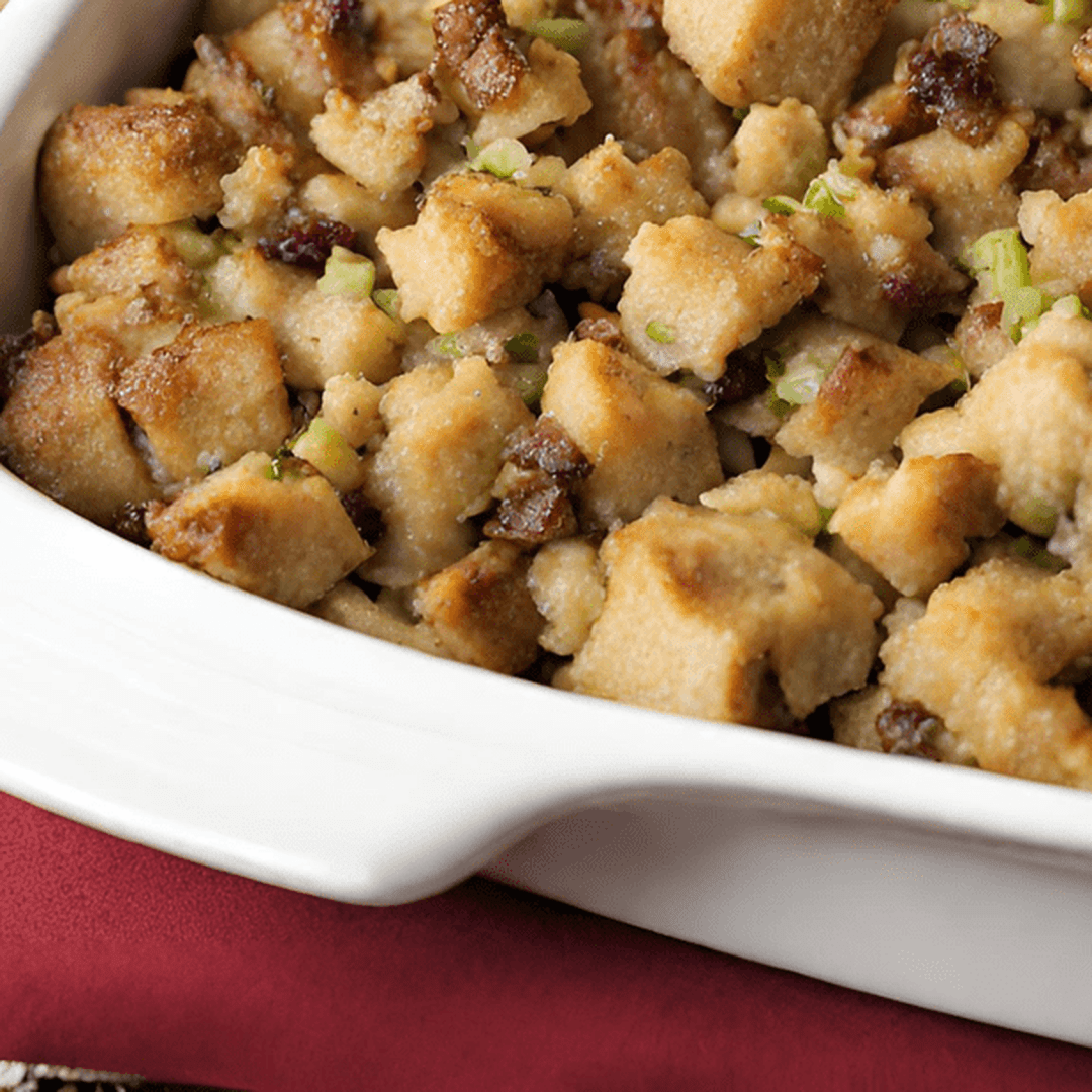 Close-up of bread-cube stuffing with chopped celery in a white baking dish.