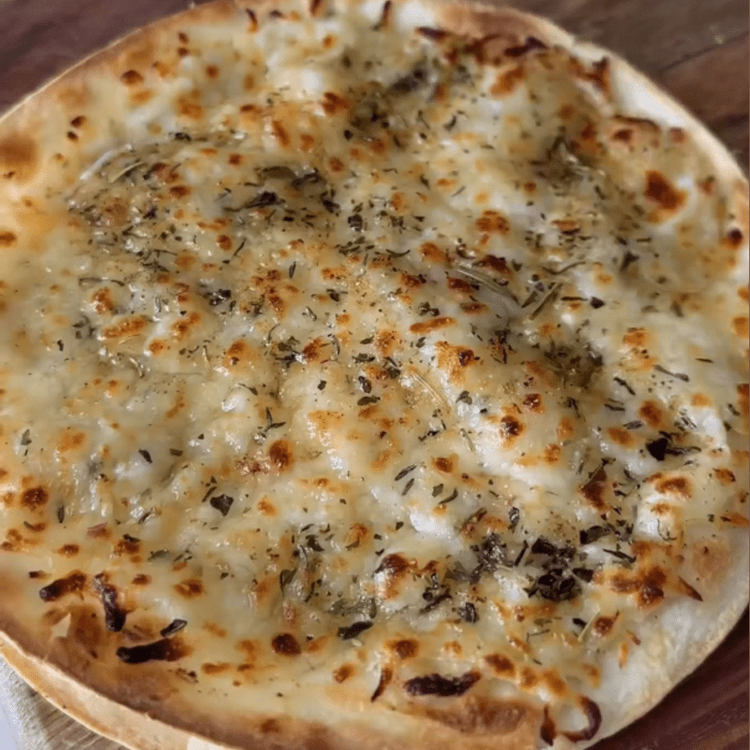 Crispy tortilla topped with melted garlic butter, bubbling browned cheese and scattered dried herbs