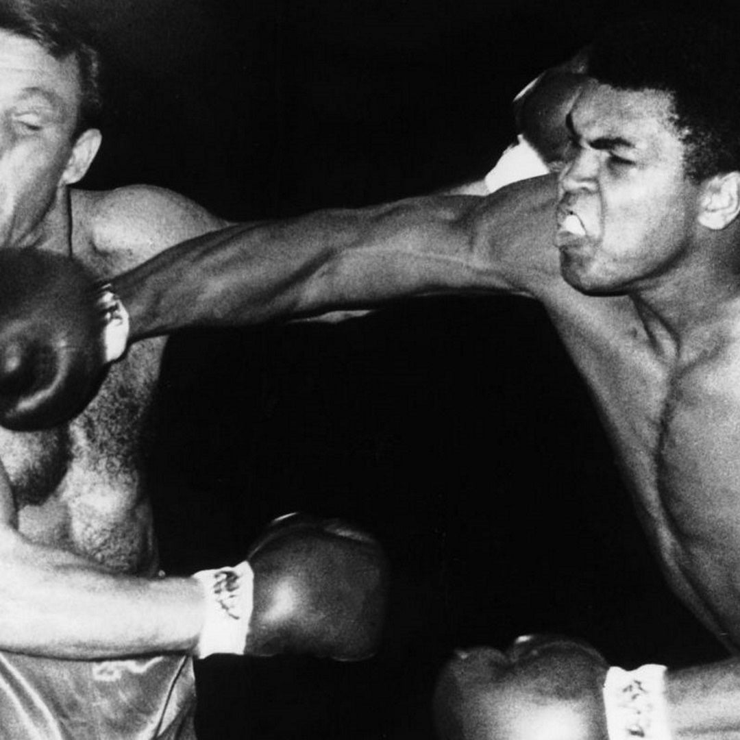 Black-and-white photo of Muhammad Ali landing a right-hand punch to Brian London's face during a match
