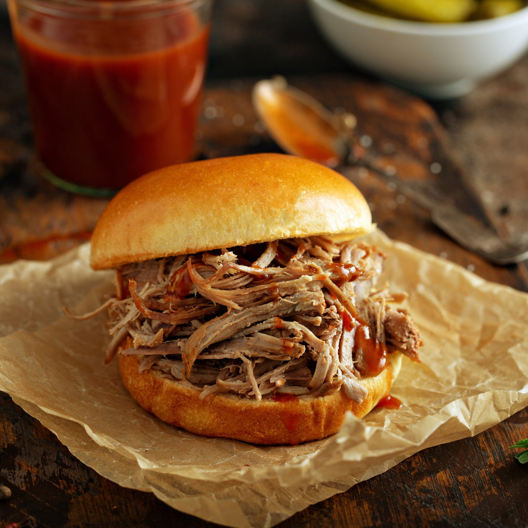 Pulled pork sandwich on a soft brioche bun with barbecue sauce, served on crinkled parchment.