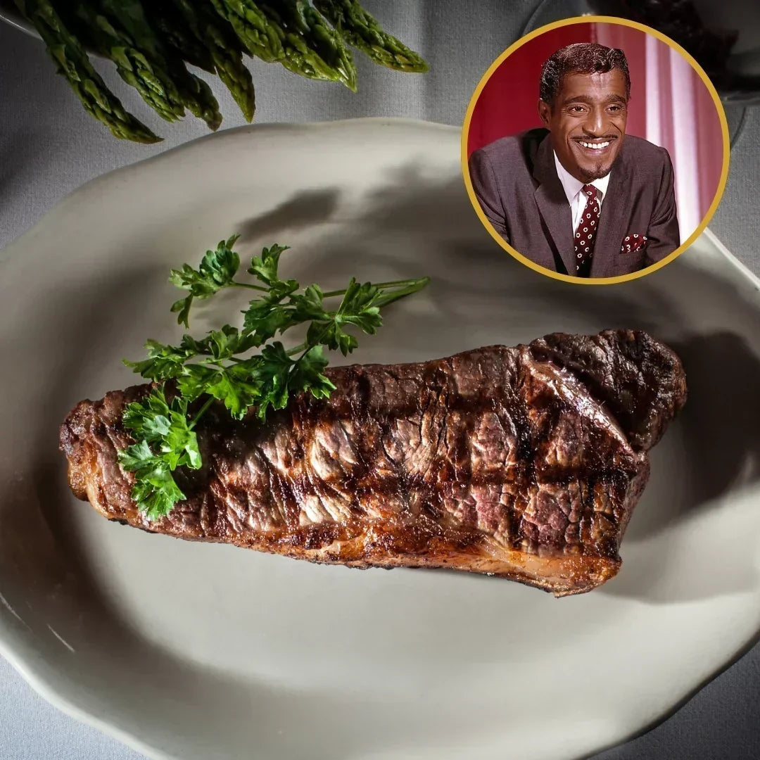 Overhead view of Sammy Davis Jr.’s favorite New York strip steak showcasing grill marks and parsley garnish on a plate with asparagus