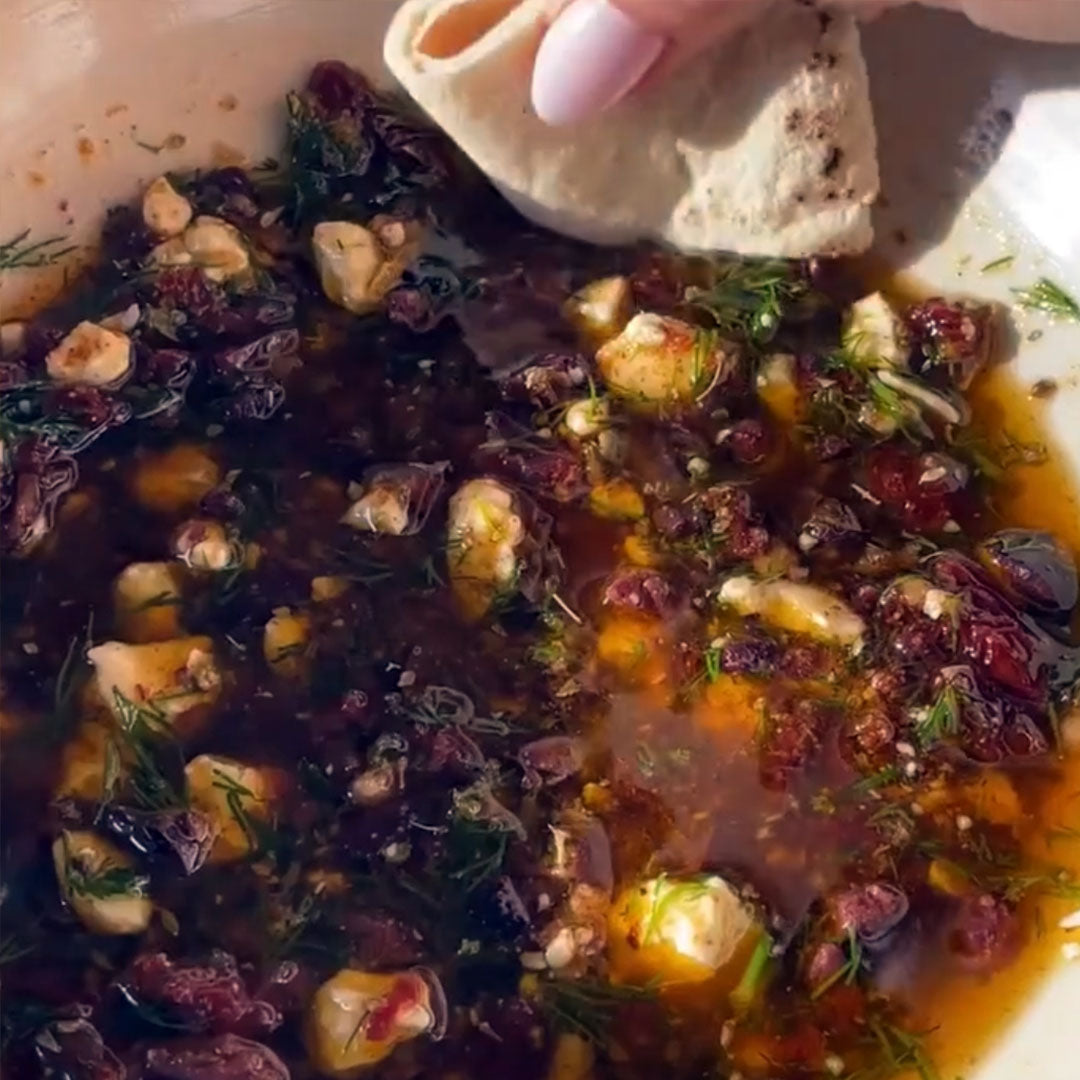 Bread with a bowl of chunky Mediterranean dipping oil studded with olives and dill