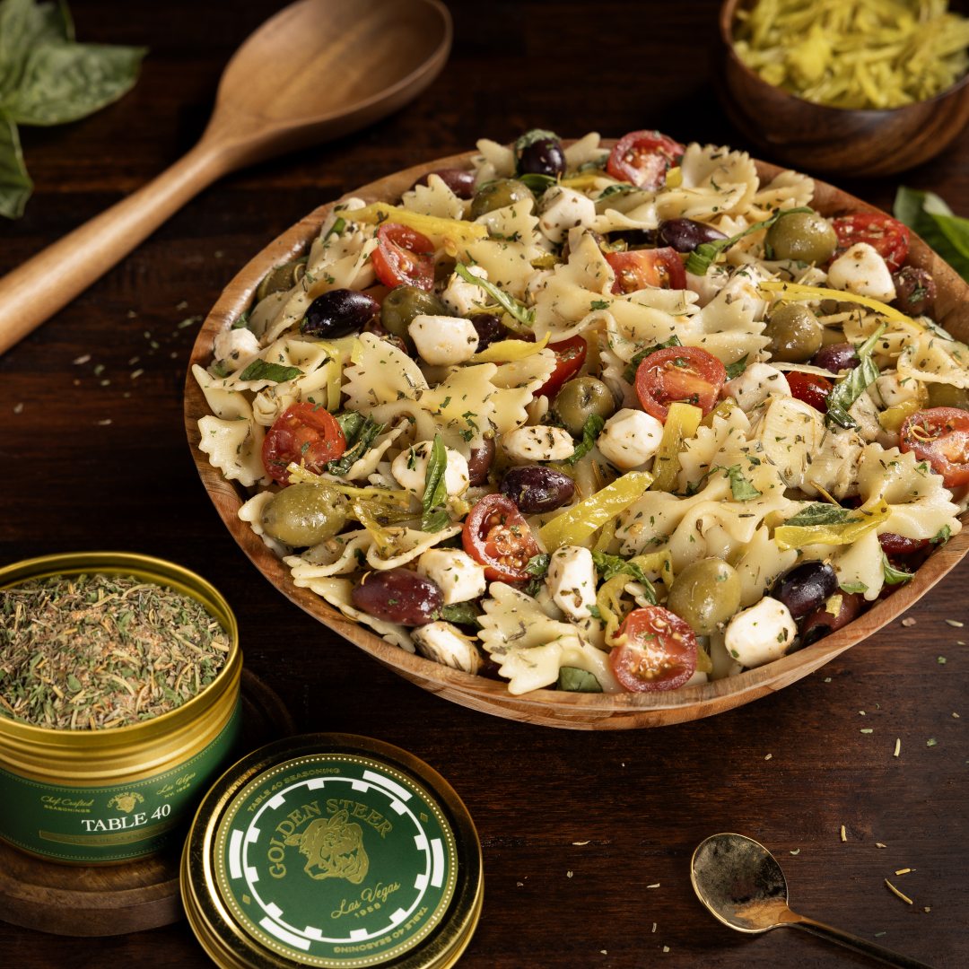 Pasta salad with tomatoes, olives and mozzarella; TABLE 40 SEASONING tin and GOLDEN STEER Las Vegas lid visible.