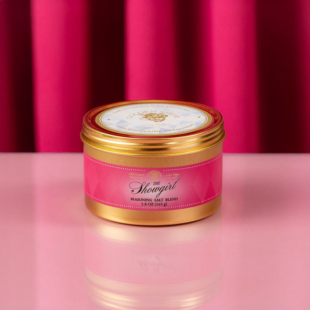 The Showgirl seasoning blend container with gold lid on a pink background