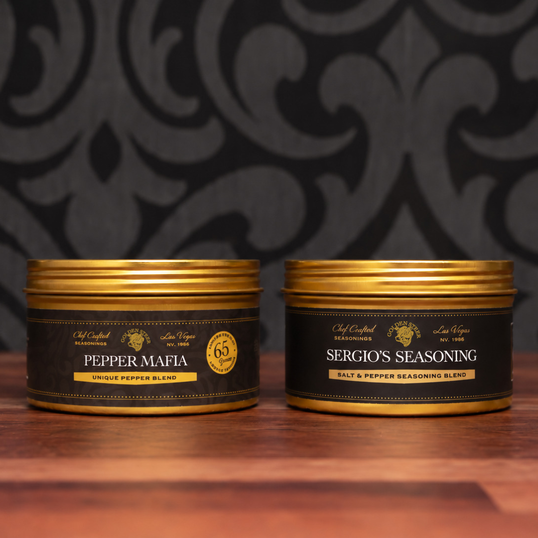 Front view of The Kitchen Essentials Duo showing Pepper Mafia and Sergio’s Seasoning tins on a wooden table