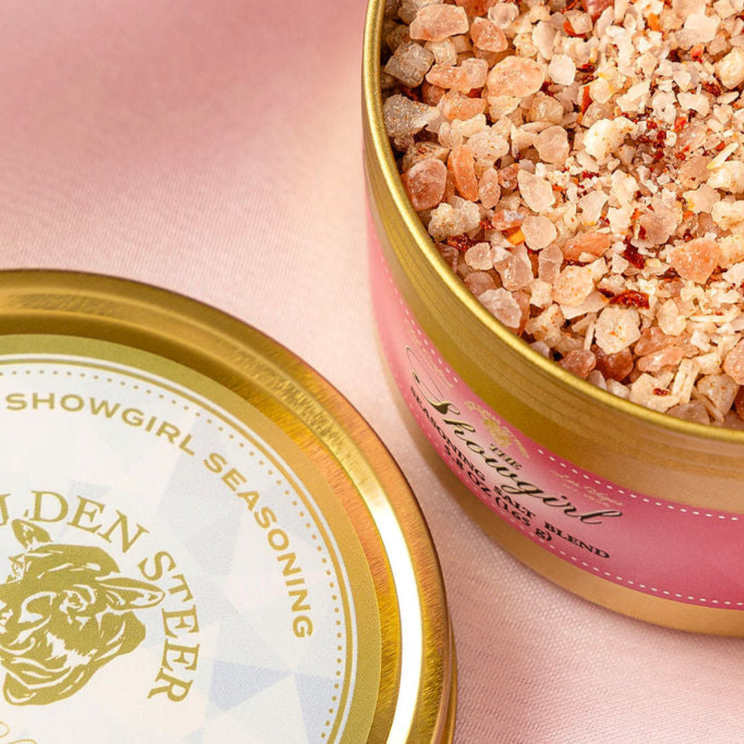 Open container of 'The Showgirl Seasoning' with visible brand name on a pink background